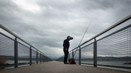 Man standing on bridge against sky