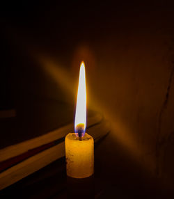 Close-up of lit candle in darkroom