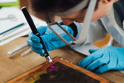 Antique religious icon restoration. female conservation using ultraviolet light to inspect damages