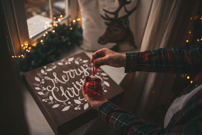 Midsection of man holding christmas decoration at home