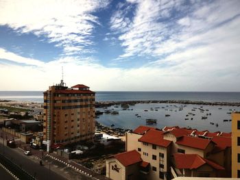 View of cityscape by sea against sky