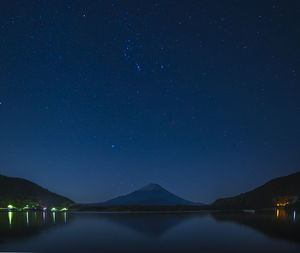 Scenic view of lake and mountains against sky at night