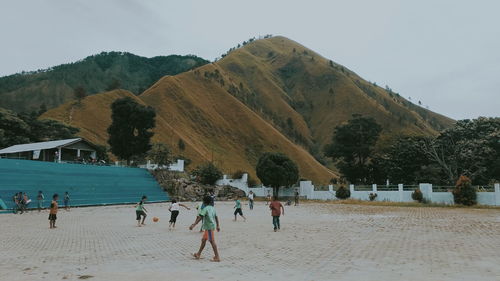 People on beach against mountains