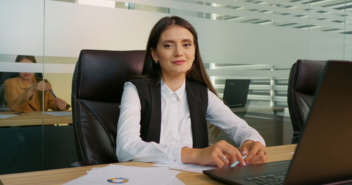 Portrait of business woman signing document and smiling on camera. 