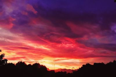 Low angle view of silhouette trees against dramatic sky