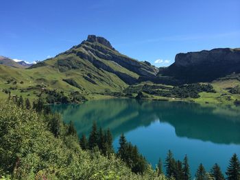 Scenic view of lake and mountains against clear blue sky