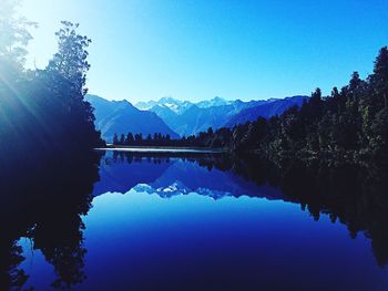 Scenic view of lake and mountains against clear blue sky