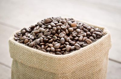 Roasted coffee beans in sack on table