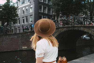 Woman sitting on canal in city