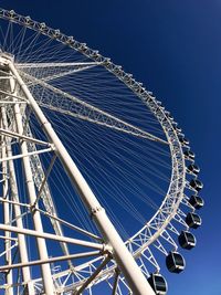 Low angle view of ferris wheel against clear blue sky