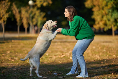 Young woman and her obedient big dog in autumn park