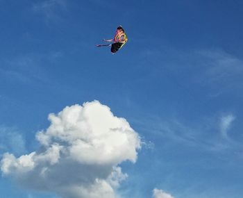 Low angle view of kite flying against cloudy sky