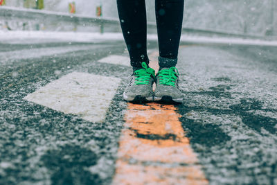 Low section of woman standing on road covered with snow