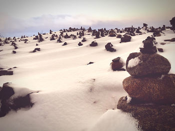 Stack of rocks on snow covered land against sky