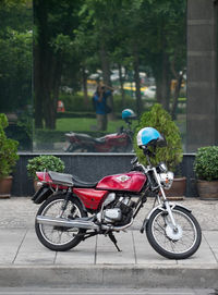 Motorcycle parked on paved walkway against glass building