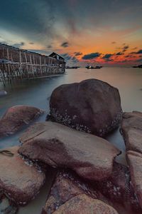 Rocks by sea against sky during sunset