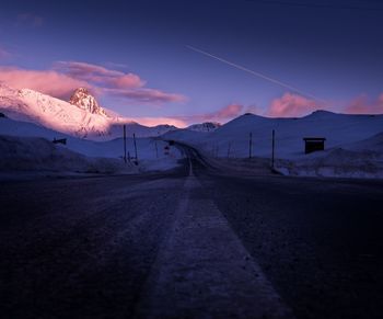 Surface level of road against mountains at sunset