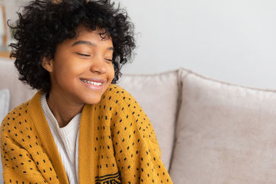 Portrait of young woman sitting on sofa at home