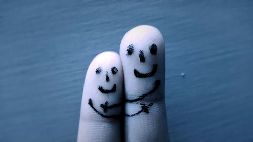 Close-up of smiles drawn on finger against wall