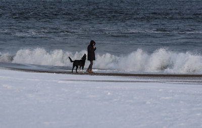 Dog playing with man against the sea