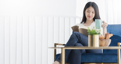 Young woman sitting on chair at home