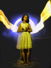 Full length of woman standing against illuminated light