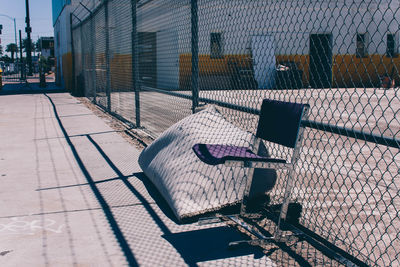 Empty chair by chainlink fence