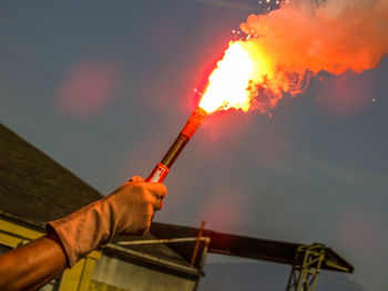 Low angle view of hand holding fire against sky