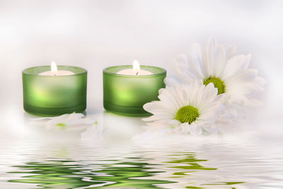 Close-up of tea light candles by flowers on table