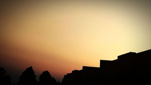 Low angle view of silhouette buildings against clear sky