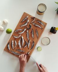 Directly above shot of man cutting sardines on breadboard