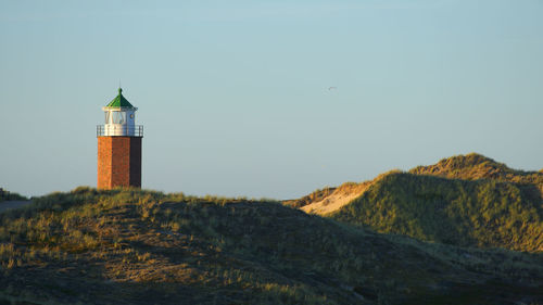 Lighthouse amidst buildings against sky