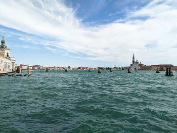 View of buildings by sea against cloudy sky