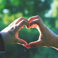 Close-up of hand holding heart shape against blurred background