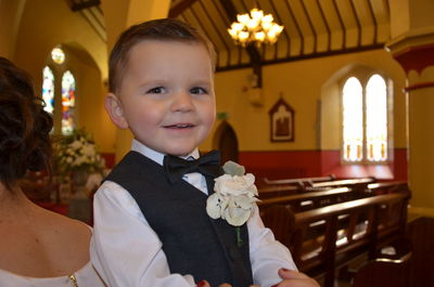 Portrait of cute boy standing by bride in church