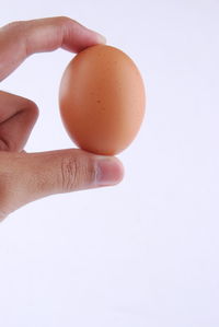 Close-up of hand holding apple against white background