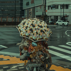 Person holding umbrella riding bicycle on street