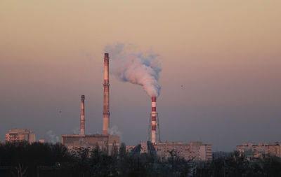 Smoke emitting from industry against sky during sunset