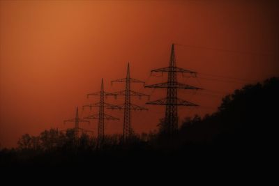 Silhouette electricity pylon against sky during sunset