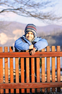 Portrait of smiling woman standing against railing