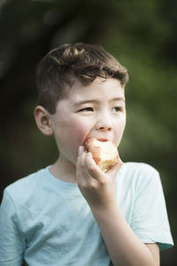 Boy eating apple while looking away