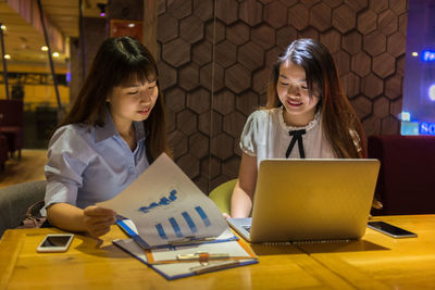 Businesswomen discussing business strategy while sitting in restaurant