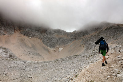 Rear view of man standing on mountain against sky