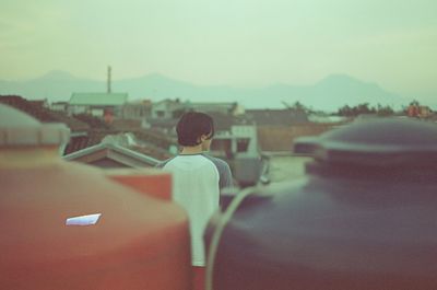 Rear view of man in city against sky