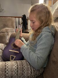 Side view of young woman sitting on sofa at home