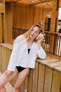 Young woman using mobile phone while standing on wood