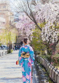 Full length of woman standing on pink cherry blossom