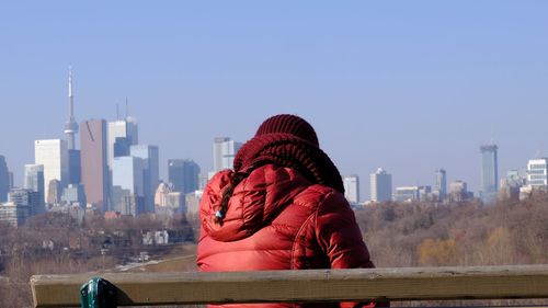 Rear view of woman looking at city against clear sky