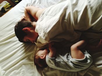 High angle view of brothers sleeping on bed