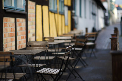 Empty chairs and tables in cafe against building